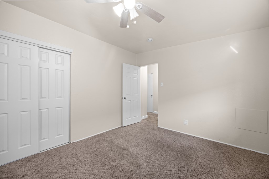 A room with a carpeted floor and a ceiling fan.