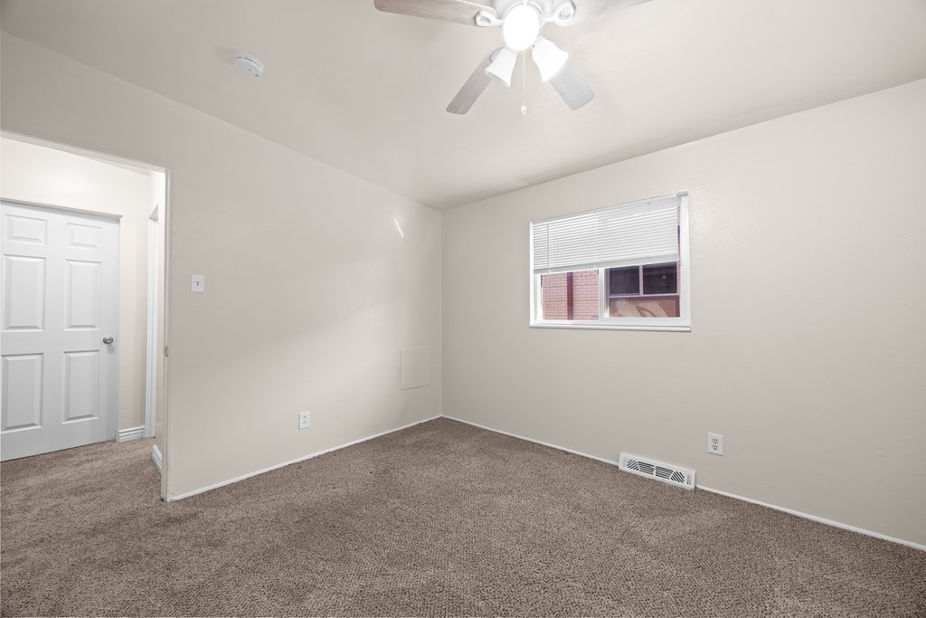 A room with a ceiling fan and carpeted floor.