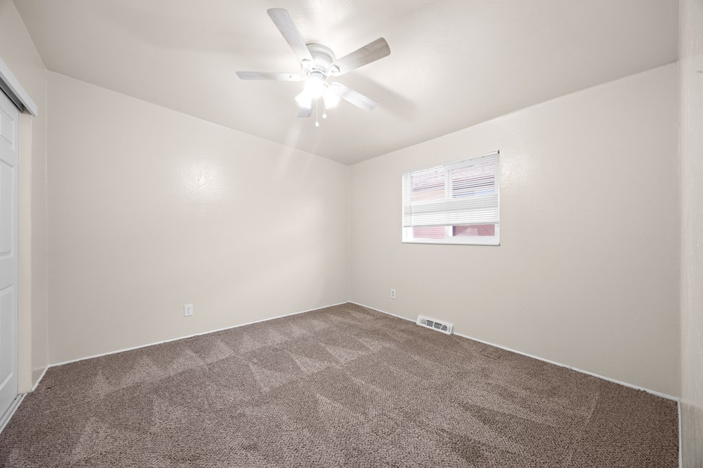 A room with a carpeted floor and a ceiling fan.
