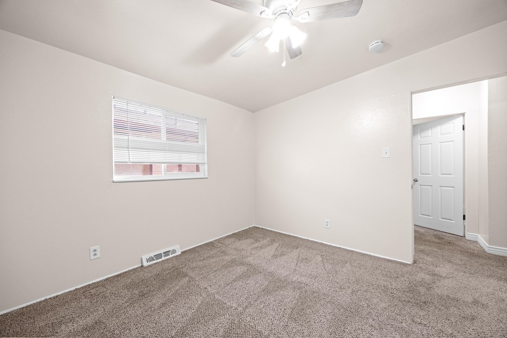 A room with a ceiling fan and a carpeted floor.