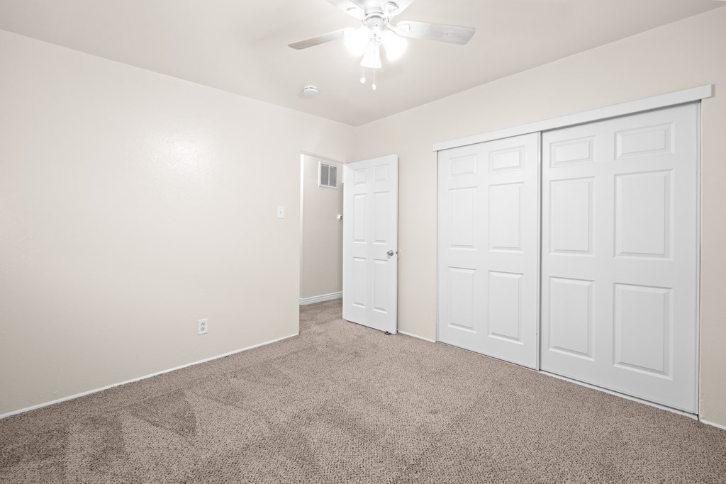 A room with a carpeted floor and a ceiling fan.