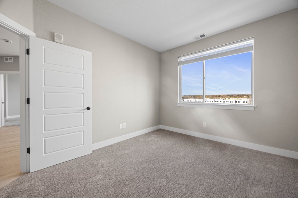 A room with a white door and a window overlooking a barren landscape.