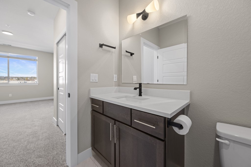 A bathroom with a sink, mirror, and toilet paper holder.