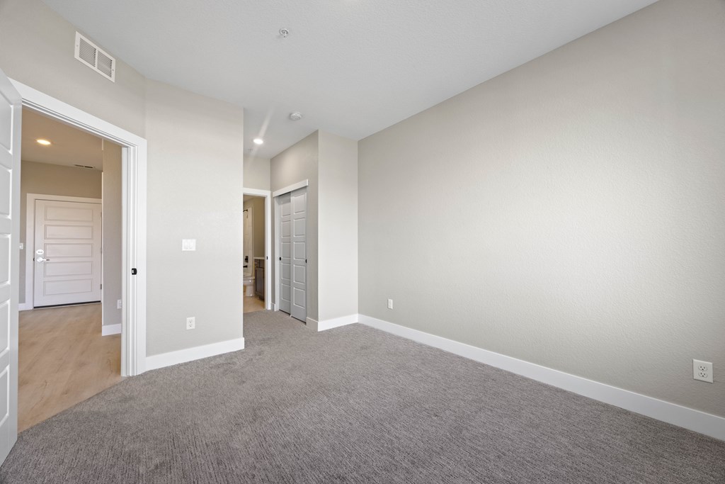 A spacious room with a carpeted floor and white walls.