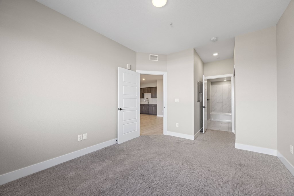 A spacious room with a carpeted floor and white walls.
