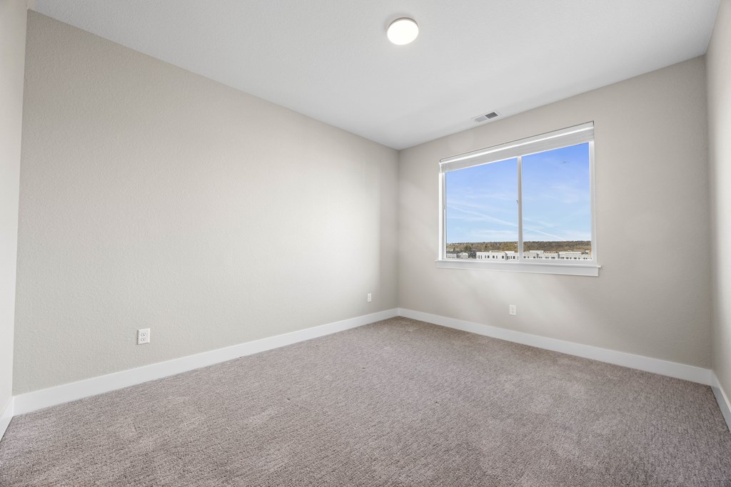 A room with a carpeted floor and a window showing a blue sky.