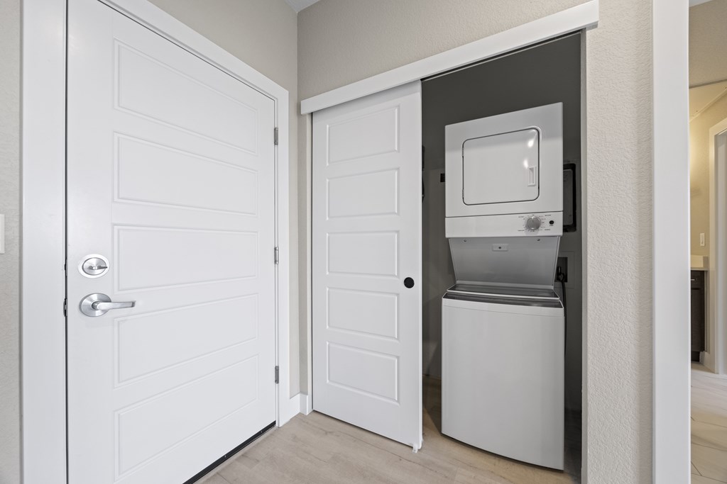 A white door is open to reveal a small kitchenette.
