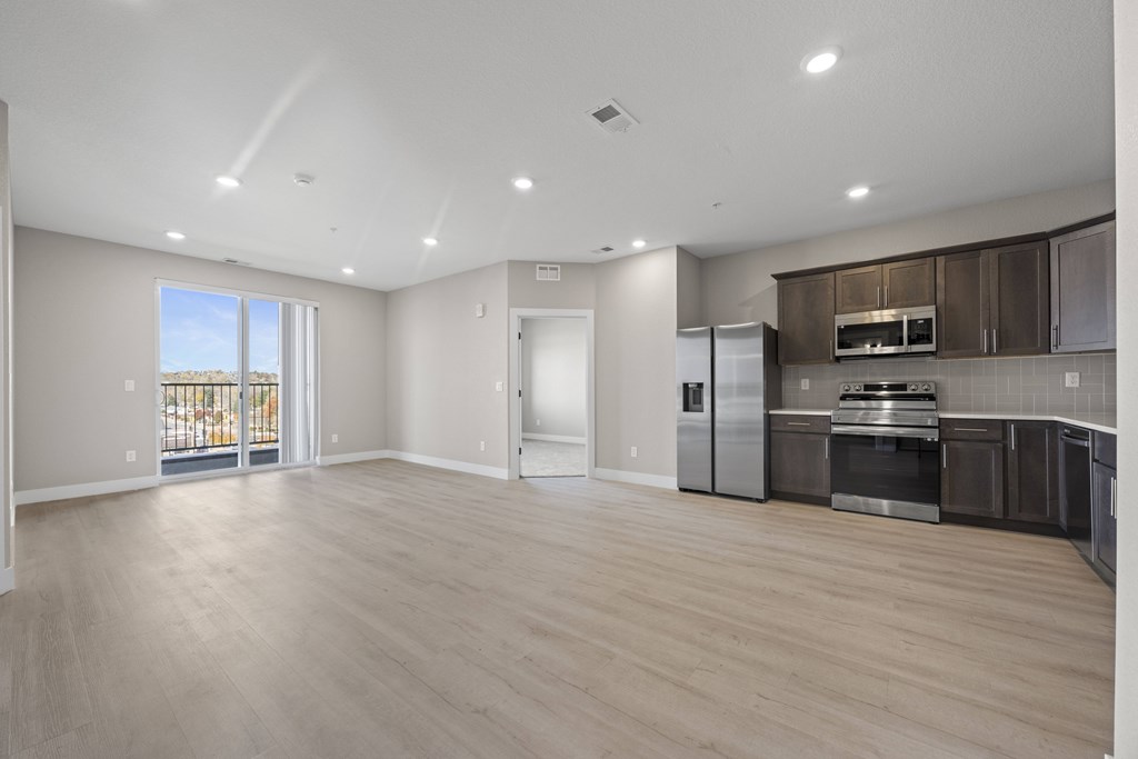 A spacious kitchen with stainless steel appliances and wooden flooring.