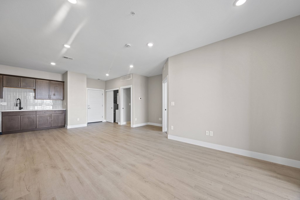 A spacious room with wooden flooring and white walls.