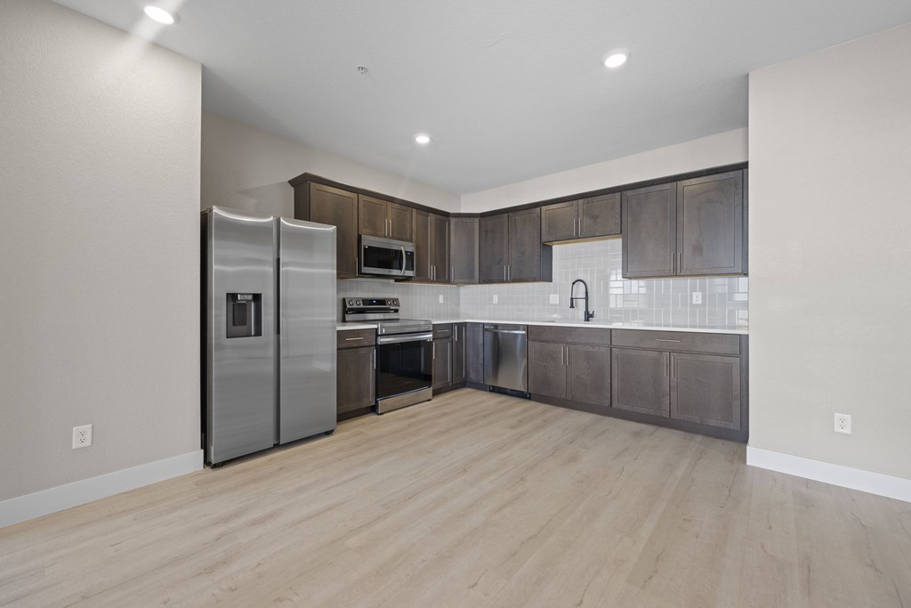 A modern kitchen with wooden floors and stainless steel appliances.