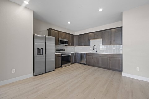 A modern kitchen with wooden floors and stainless steel appliances.