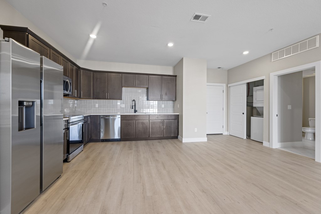 A modern kitchen with stainless steel appliances and wooden floors.