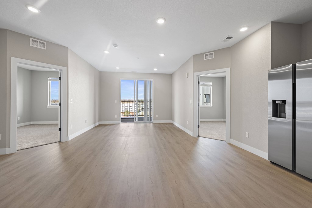 A spacious, empty room with wooden floors and white walls.