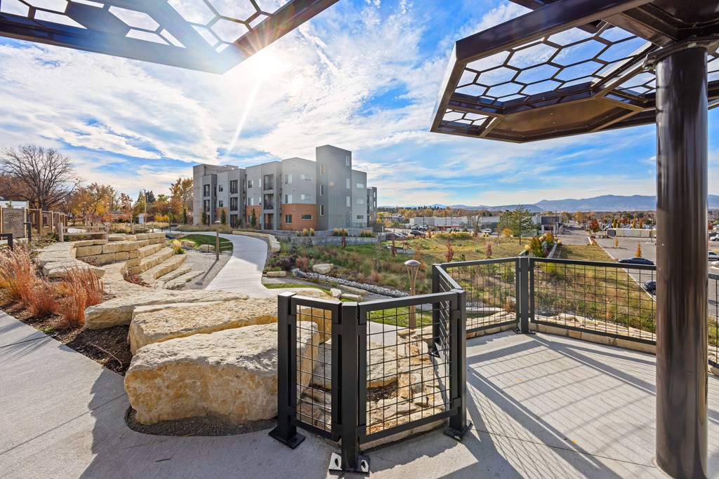 A modern building with a glass facade is surrounded by a metal fence and a stone pathway.