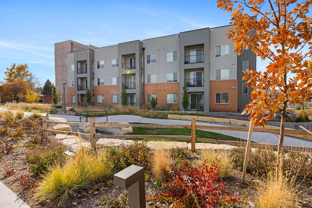 A modern apartment complex with a landscaped courtyard in the foreground.