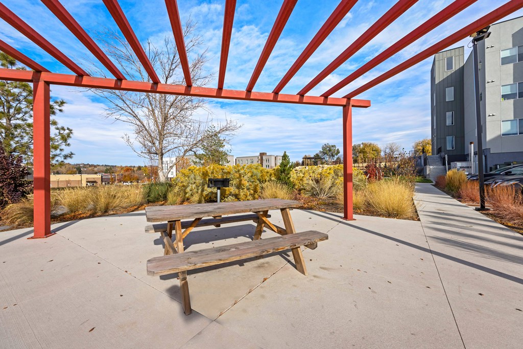 A picnic table is under a red canopy.