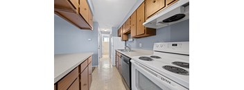 A kitchen with a white stove top oven and wooden cabinets.