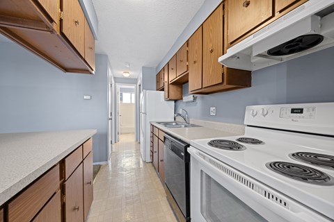 A kitchen with a white stove top oven and wooden cabinets.