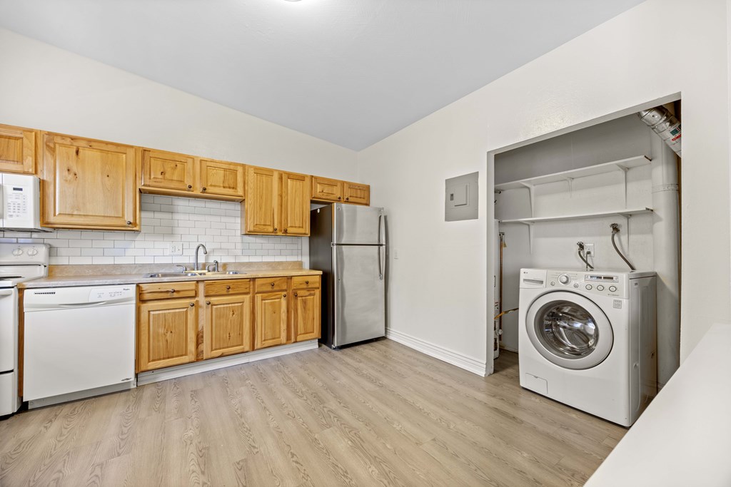 A kitchen with wooden cabinets and a washing machine in the corner.
