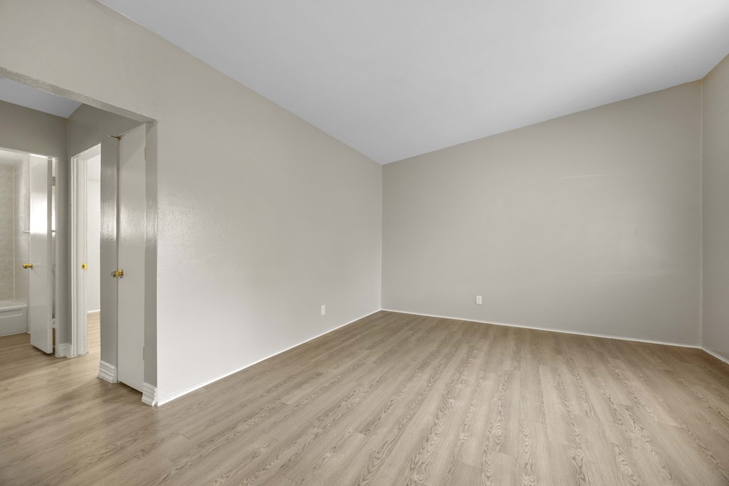 A room with wooden flooring and white walls.