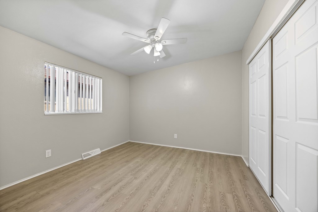 A room with a ceiling fan and a window with blinds.