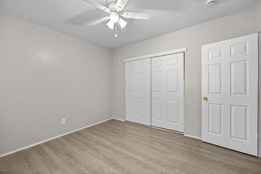 A room with a ceiling fan and two doors.