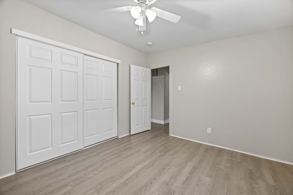 A room with a white door and a ceiling fan.