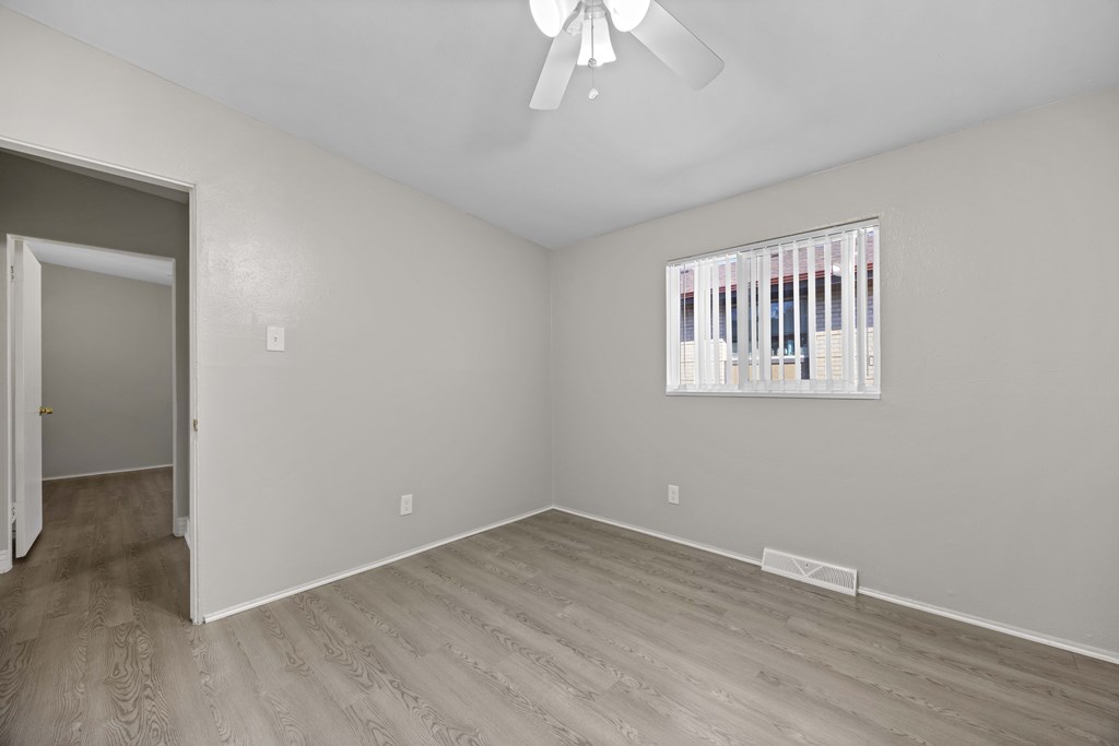 A room with a ceiling fan and a window with blinds.