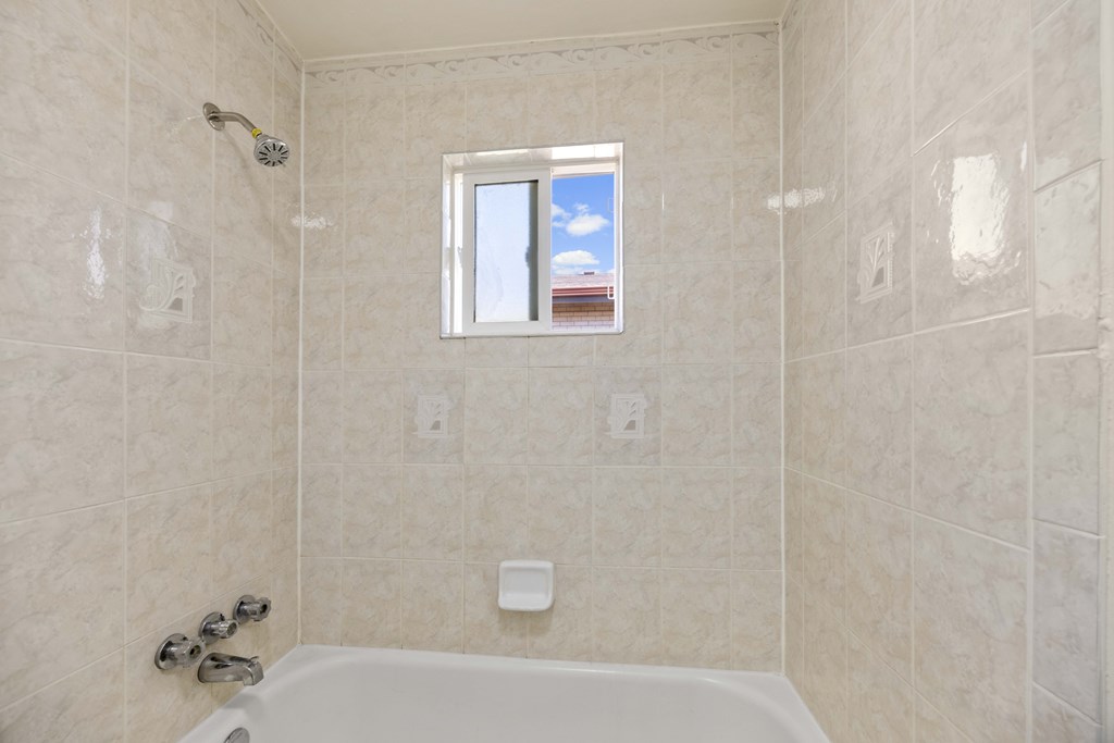 A bathroom with a white tub and a window.