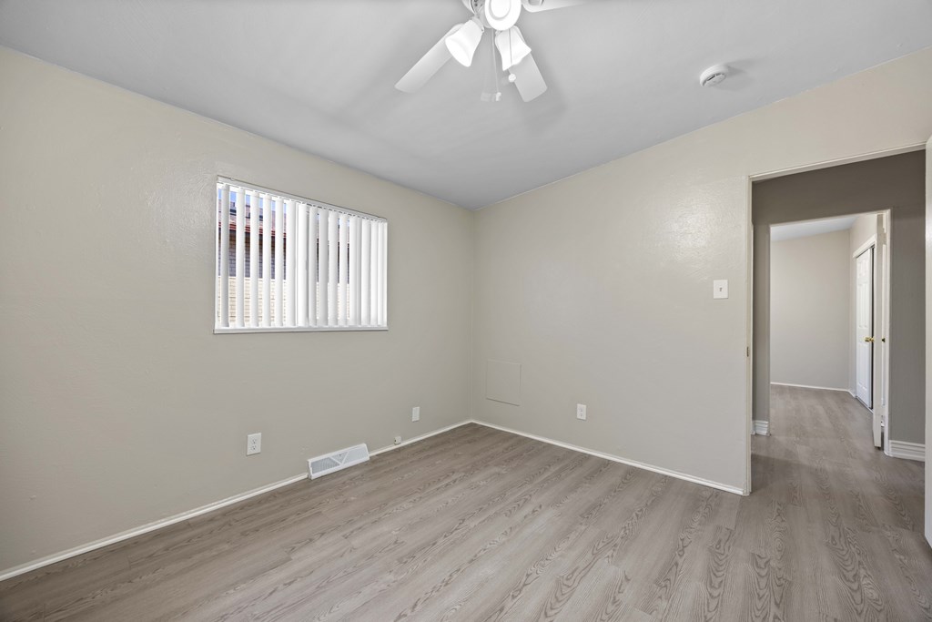 A room with a window and a fan on the ceiling.