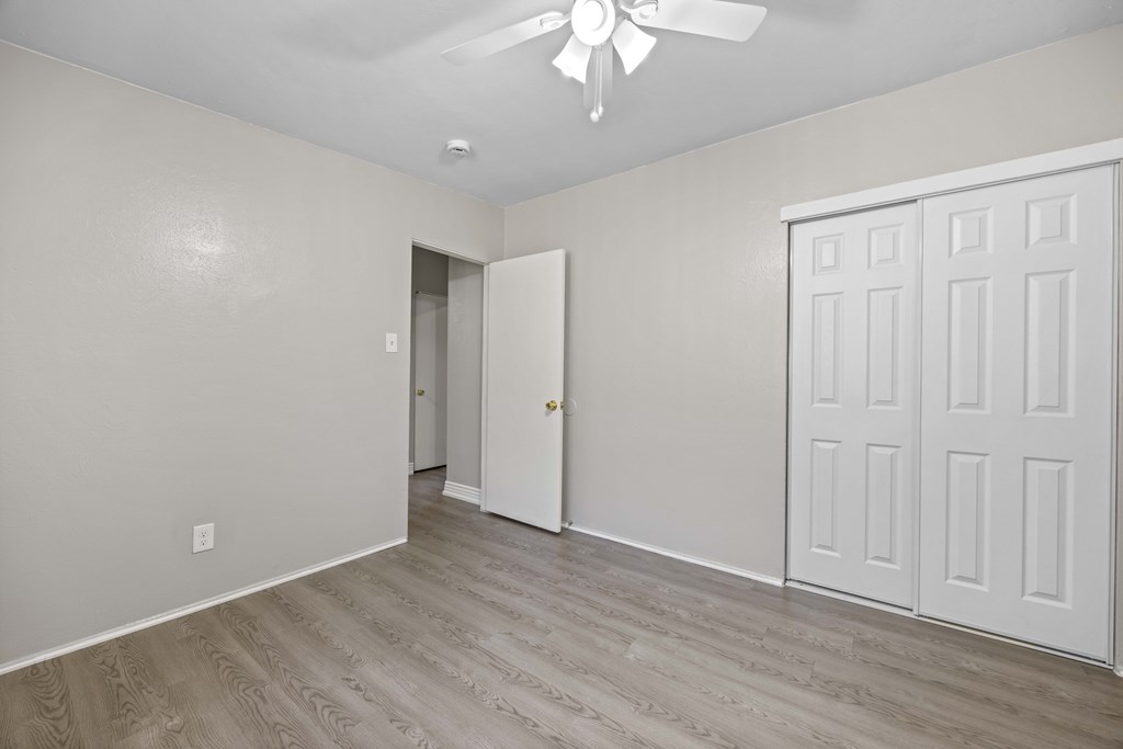 A room with a white door and a ceiling fan.