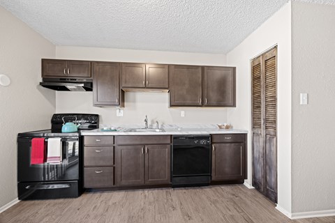 A kitchen with brown cabinets and black appliances.