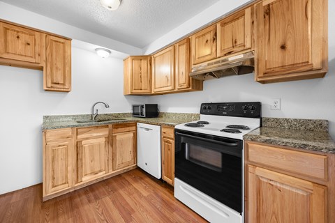 A kitchen with wooden cabinets and a white stove top oven.