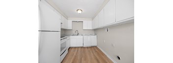 A kitchen with white cabinets and a wooden floor.