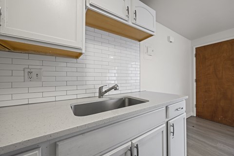 A kitchen with white cabinets and a white sink.
