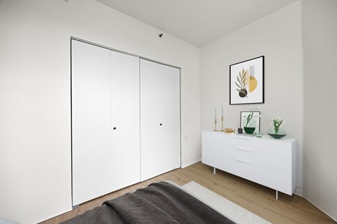 A white room with a grey rug and a white cabinet with a plant on top at Tallmadge Lofts in Denver, CO