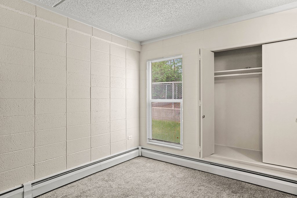 an empty room with a window and a closet