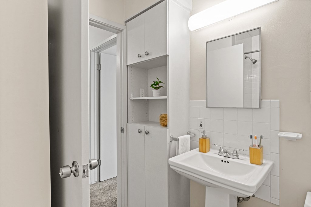 a small bathroom with a white sink and mirror