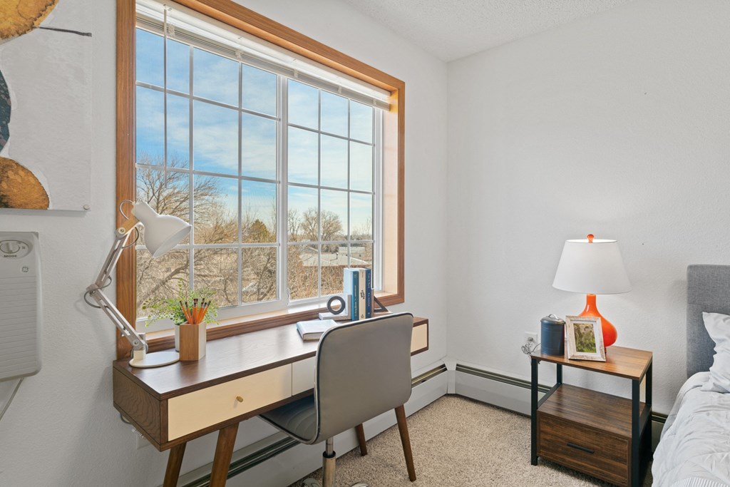 a bedroom with a large window and a desk with a chair