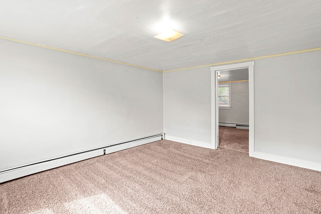 A room with a carpeted floor and a doorway leading to another room.