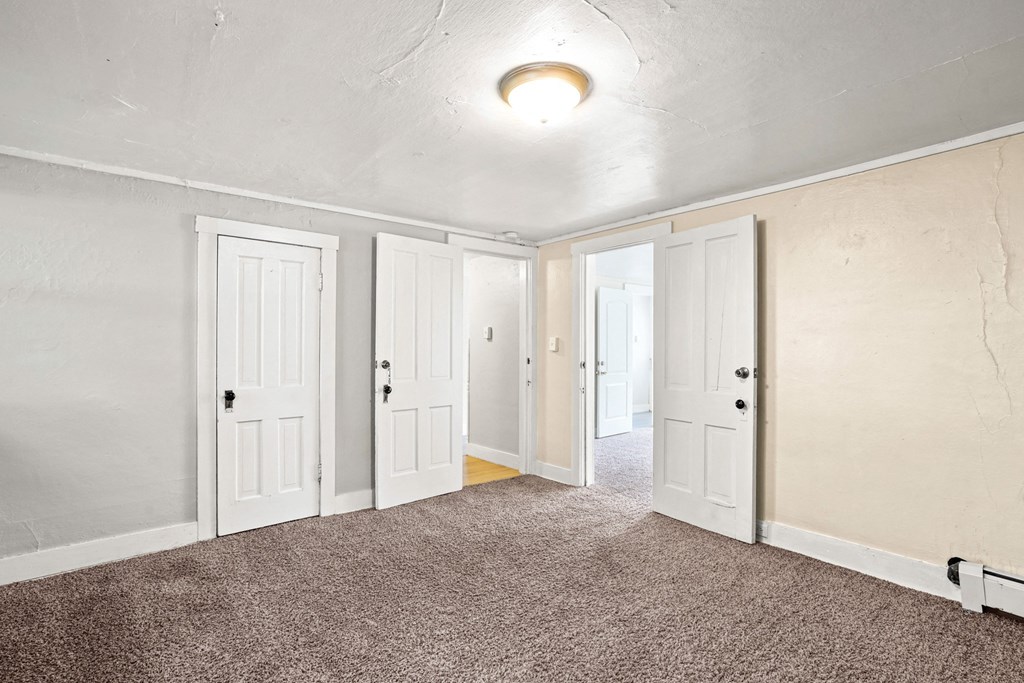 A room with four doors and a carpeted floor.