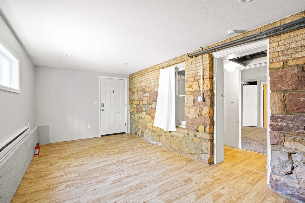 A room with wooden floors and a stone wall.