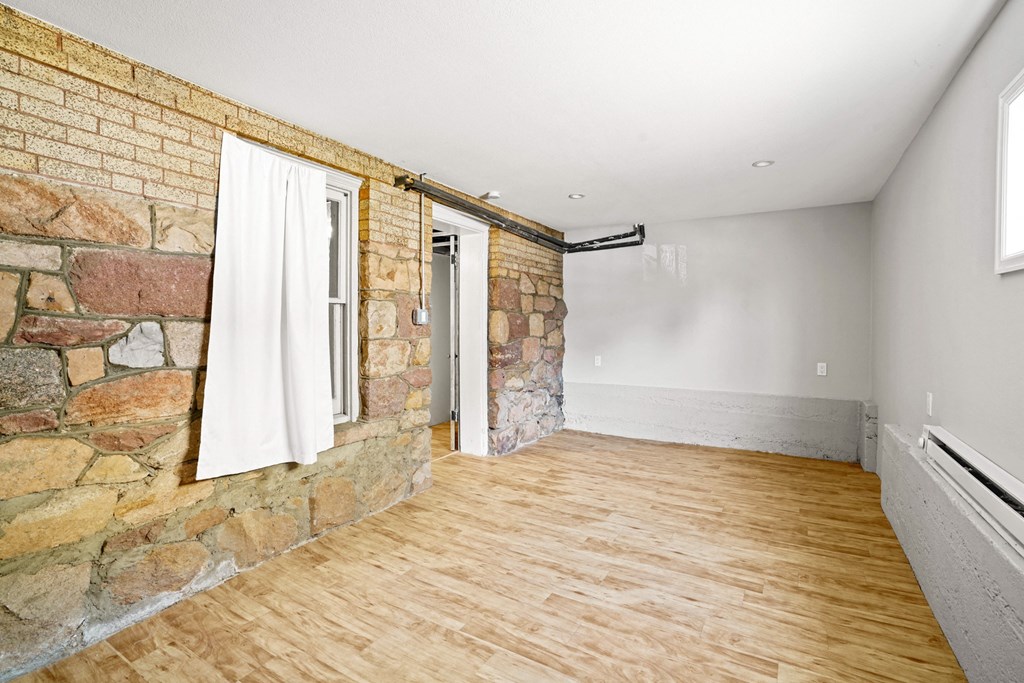 A room with a stone wall and wooden flooring.
