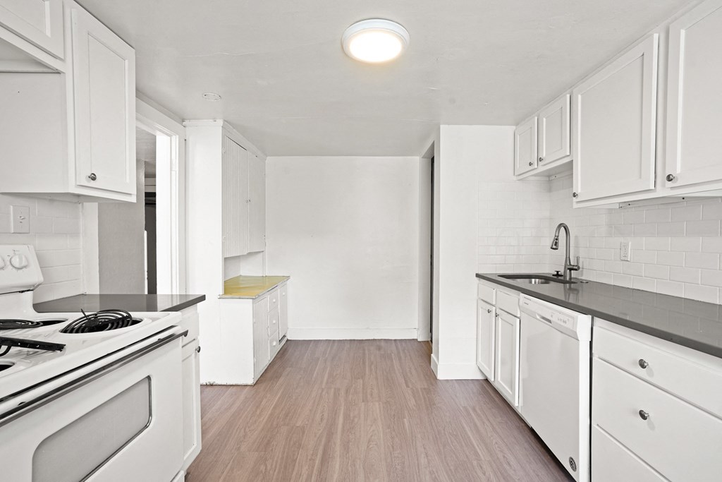 A kitchen with white cabinets and a black stove top.