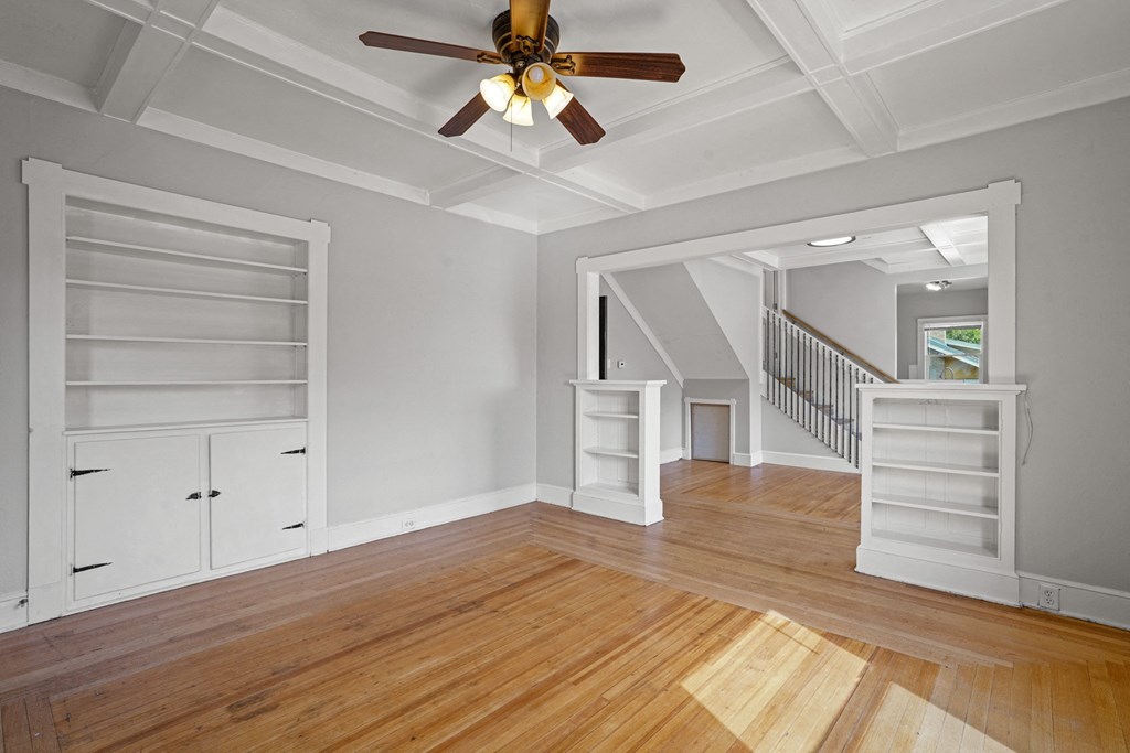 A room with a ceiling fan and wooden floors.