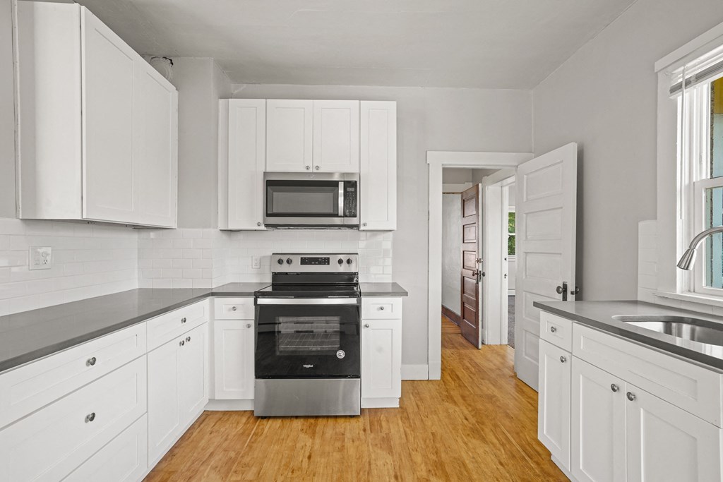 A kitchen with white cabinets and a stainless steel oven.