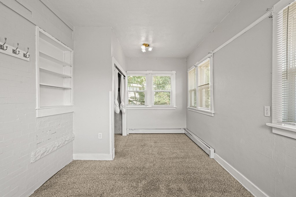 A white room with a carpeted floor and a window.