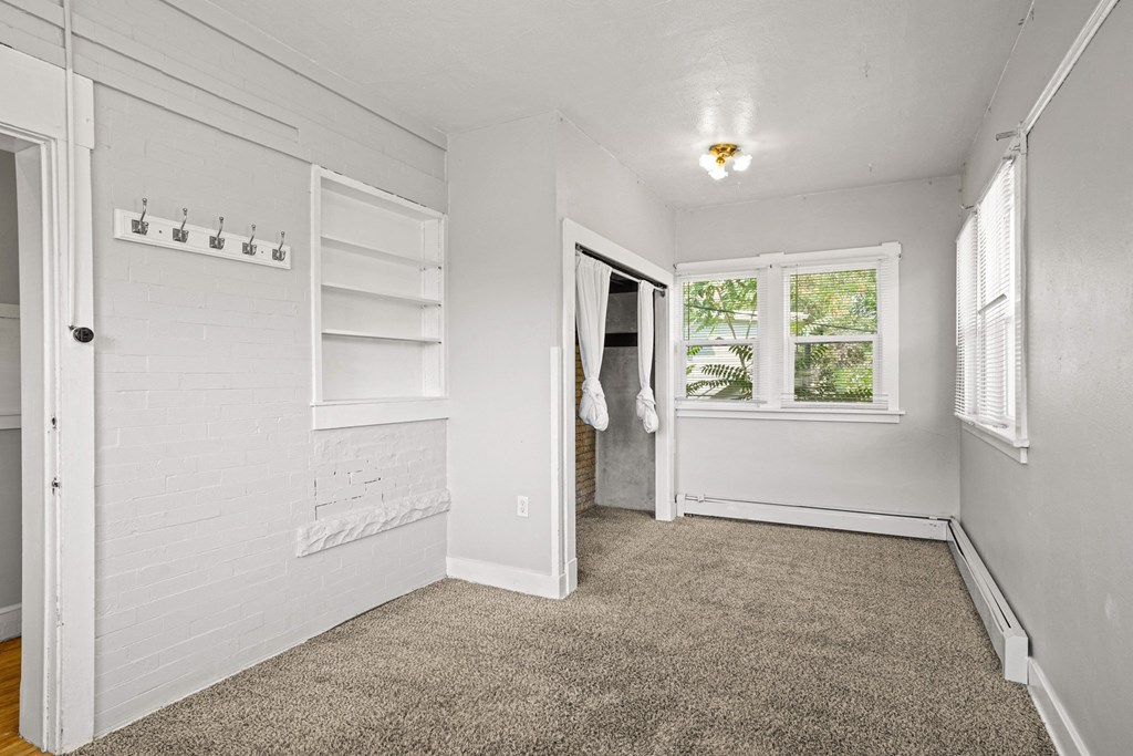 A white room with a carpeted floor and a window.