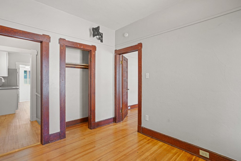 A room with a white wall and a brown wooden floor.