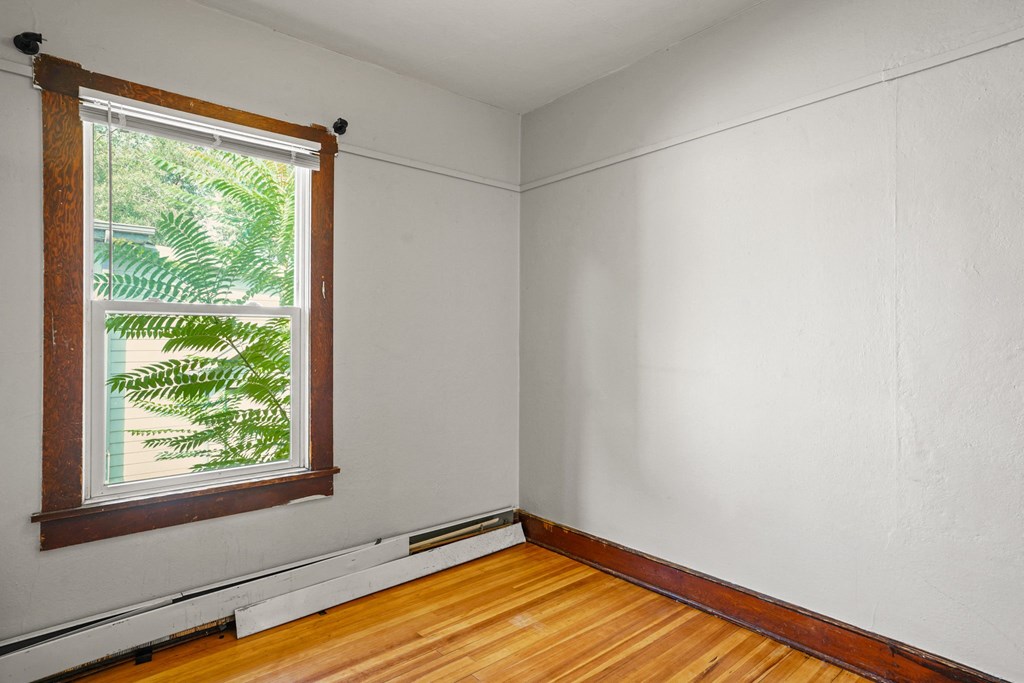 A room with a window and wooden floors.